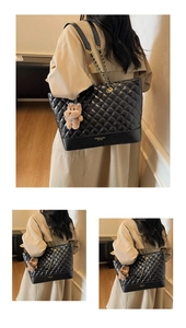 Close-up of black quilted tote bag with chain strap and cute teddy bear charm detail