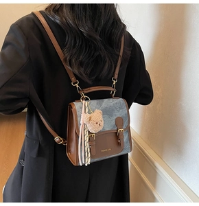 Gros plan sur un sac à dos en denim bleu et cuir brun avec breloque ours en peluche