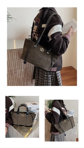 Detail of dark brown suede tote bag featuring gold metal rings and leather chain strap