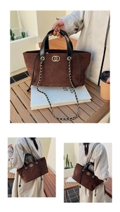 Detail of brown suede tote bag with golden metal logo and chain strap accents