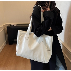 Close-up of white leather tote bag with NOCOBAG logo and elongated shoulder straps