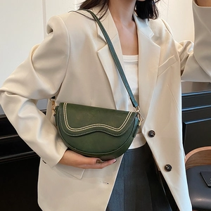 Dark green leather crescent saddle bag with beaded trim and gold hardware on a model