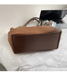 Detailed view of durable stitching on a brown suede tote bag in a casual home setting