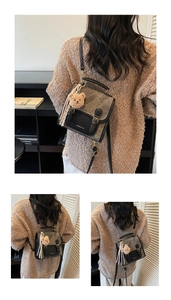Détail d'un sac bandoulière vintage gris avec breloque ours et gland sur un pull-over