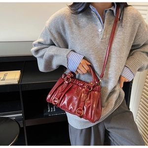 Detail of red patent leather handbag with vertical pleats and golden ring hardware