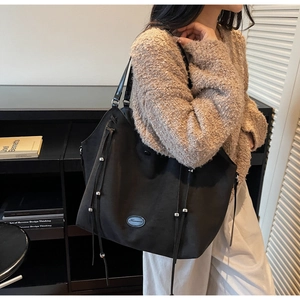 Détail du sac cabas noir mat avec des perles argentées et des cordons ajustables