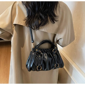 Detail of black glossy leather cloud bag with gold rings and studded hardware