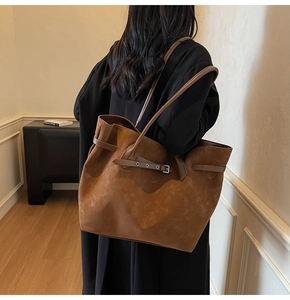 Detail view of caramel brown suede tote bag featuring a leather strap and buckle accent