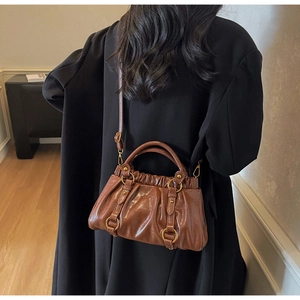 Brown pleated vintage handbag with large gold rings worn over a black winter coat