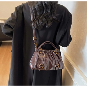 Detail view of coffee brown pleated shoulder bag with gold metal ring accents and glossy finish