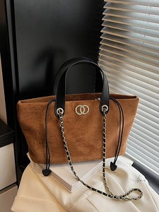 Brown suede tote bag with dual gold rings and chain strap in a lifestyle setting