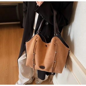 Close-up of caramel suede tote bag with fringe details and silver beads on a model