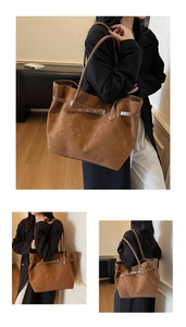 Detail of a large brown suede tote bag with decorative buckle strap and dual handles