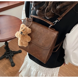Detail of vintage brown leather backpack with letter embossing and cute bear charm