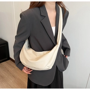 Minimalist cream crescent crossbody bag shown on model with chic urban fashion style