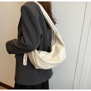 Side view of large crescent shoulder bag in cream PU leather with gathered handle detail