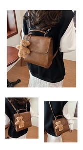 Detail of vintage brown PU leather backpack with embossed logo and plush bear charm