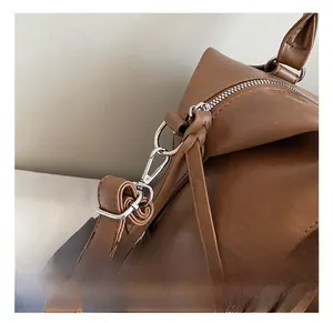 Detailed macro view of silver metal carabiner hook and stitching on brown leather bag