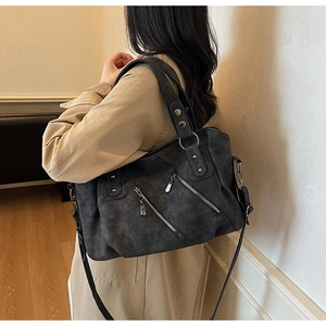 Detail of dark grey large tote bag with multiple pockets and rivets worn with beige coat