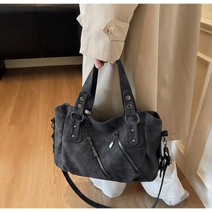 Close-up of a dark grey matte tote bag with diagonal zippers and metal stud detailing