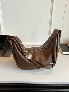 Deep brown oil wax leather dumpling crossbody bag with silver hardware on white background