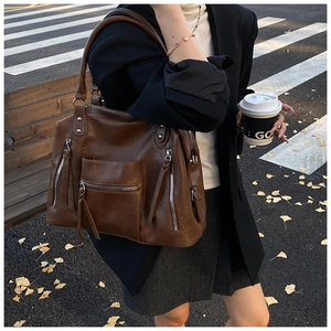 Detail view of large dark brown retro PU leather tote bag worn on shoulder in autumn