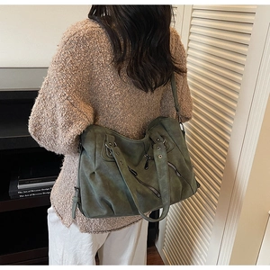 Close-up of a large green hobo bag with vintage matte leather texture and metal buckles