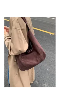 Detailed view of deep brown suede hobo tote with wide shoulder strap on model