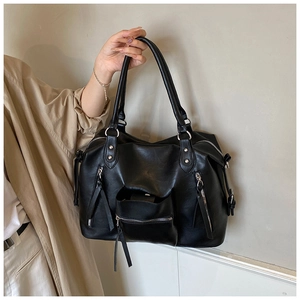 Detail of a large black tote bag featuring multiple zipper pockets and silver hardware