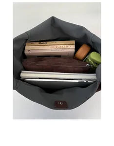 Top view of a large dark grey tote bag interior holding a laptop, books, and accessories