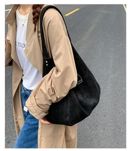 Detail of black suede hobo tote bag featuring side silver rivet studs and a soft texture