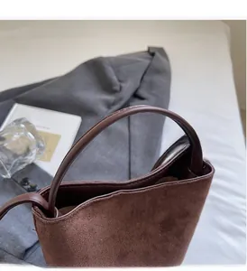 Gros plan détaillé du sac seau léopard marron montrant la texture daim et l'anse en cuir