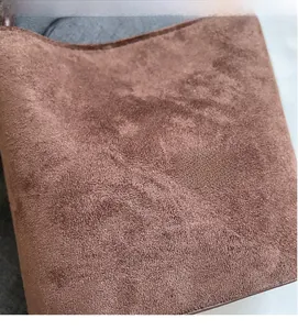 Gros plan sur la texture du cuir givré marron et les coutures précises du sac à main