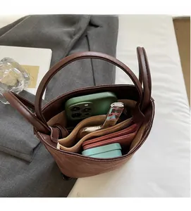 Vue de dessus montrant l'intérieur spacieux et les compartiments du sac seau en daim brun