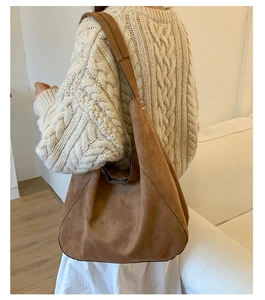 Brown suede tote bag with silver rivets shown on shoulder with autumn sweater