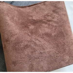 Vue macro montrant la texture mate douce et le daim marron du sac seau au style rétro