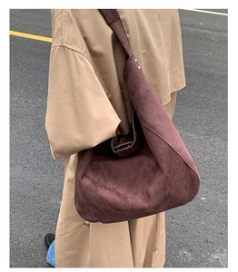 Outdoor street style shot of a large brown suede hobo bag worn with a beige trench coat