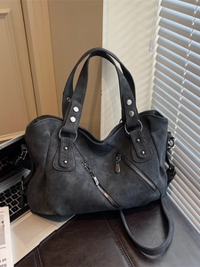 Large dark grey suede tote bag with metal zippers and crossbody strap in a modern office