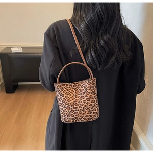 Vue arrière d'un mannequin portant un sac seau léopard avec poignées en cuir marron