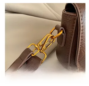 Vue macro des ferrures dorées et détails de la bandoulière en cuir marron grainé