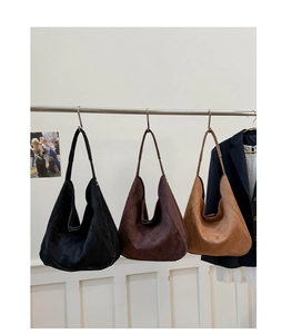 Detailed display of vintage suede tote bags in black and brown on a minimalist steel rack