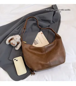 Detailed view of the dark brown leather half-moon tote with a phone for scale