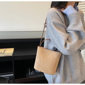 Sac seau minimaliste en daim kaki avec fine bandoulière marron porté par un mannequin