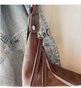Detail of a smooth silver zipper and rivets on a brown vintage suede shoulder tote bag