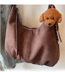 Detail of dark brown suede hobo bag with zip closure and cute poodle plush pendant