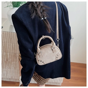 Beige mini handbag with vintage metal studs and adjustable strap shown on shoulder