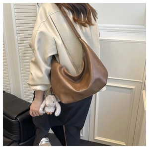 Detail of vintage brown leather hobo bag with a cute white bunny plush pendant