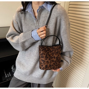 Détail du sac seau à motif léopard avec texture fausse fourrure et poignée noire