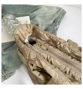 Macro view of khaki quilted tote bag showing top zipper and inner pocket details