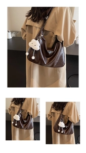 Détails d'un sac hobo en cuir marron foncé avec logo métallique et breloque nuage